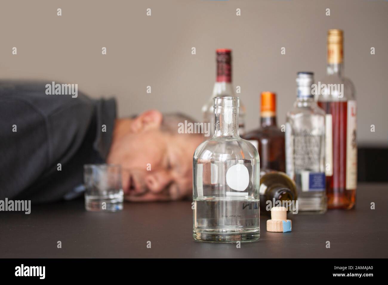 Drunken man sleeping with his head lying on a table and open mouth and