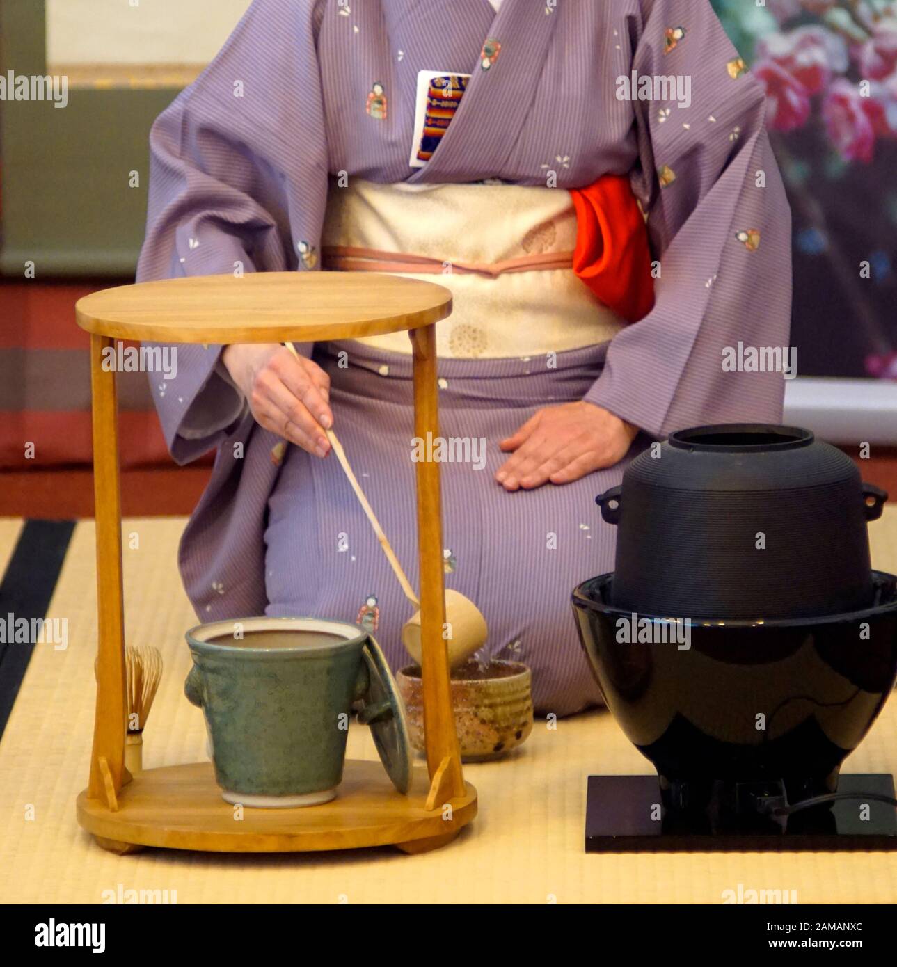 Japanese tea ceremony Chanoyu. Woman dressed in traditional kimono pors hot water with chashaku into the tea bowl. Stock Photo