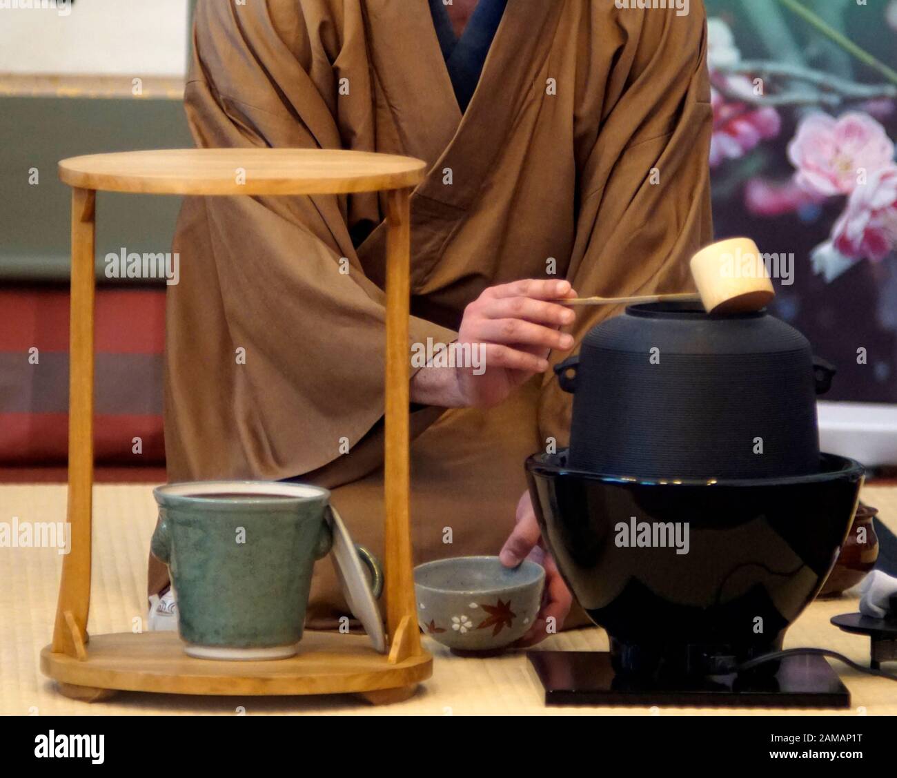 Japanese tea ceremony Chanoyu. Woman dressed in traditional kimono pors hot water with chashaku into the tea bowl. Stock Photo
