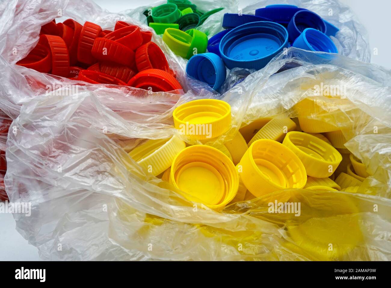 Colorful plastic bottle caps sorted by colors in transparent single use plastic bags. PP an PET pollution. Recycling solutions for plastic waste. Stock Photo