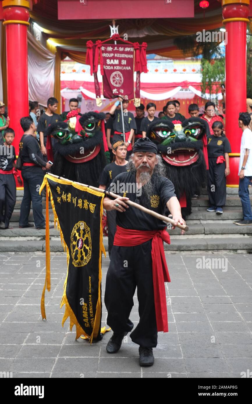 A senior man, with a flag, leads a group of lion dance artist in Chinese new year celebration festival. Stock Photo