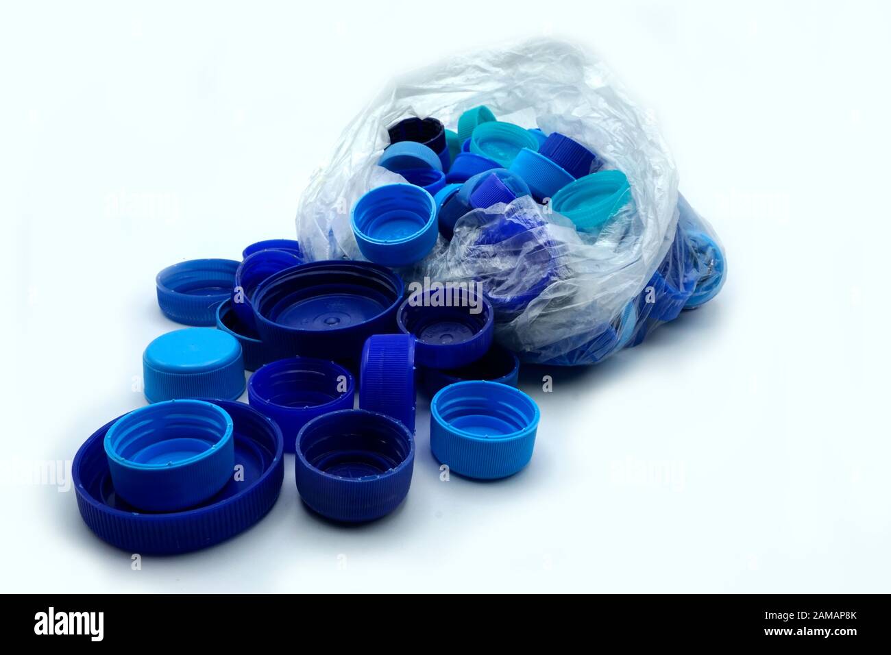Blue plastic bottle caps sorted by colors in transparent single use plastic bags. PP an PET pollution. Recycling solutions for plastic waste. Stock Photo