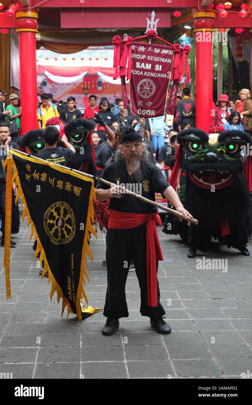 A senior man, with a flag, leads a group of lion dance artist in Chinese new year celebration festival. Stock Photo
