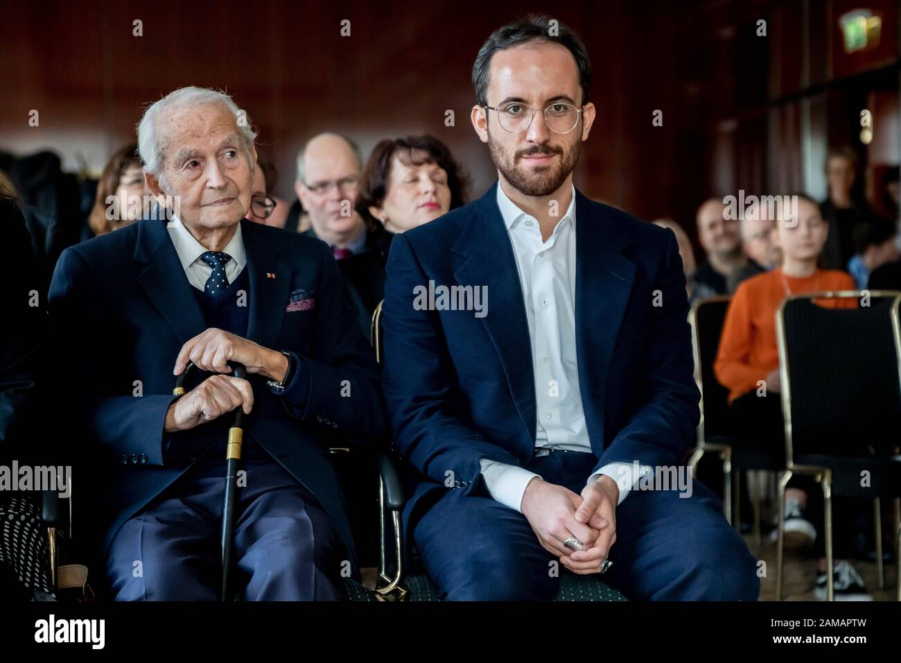 12 January 2020, Berlin: Igor Levit (r), pianist, and Leon Schwarzbaum, Holocaust survivor, sit next to each other with the statue 'B' as a 'Gift of Memory' at an event to honour Levit by the International Auschwitz Committee at the Maritim Hotel Berlin. The statue is modelled on the letter 'B' in the lettering 'ARBEIT MACHT FREI' above the Auschwitz gate, which the prisoners in Auschwitz had secretly turned upside down when they had to manufacture the sign on the orders of the SS. For the prisoners this action was a sign of their human dignity and resistance. Photo: Christoph Soeder/dpa Stock Photo