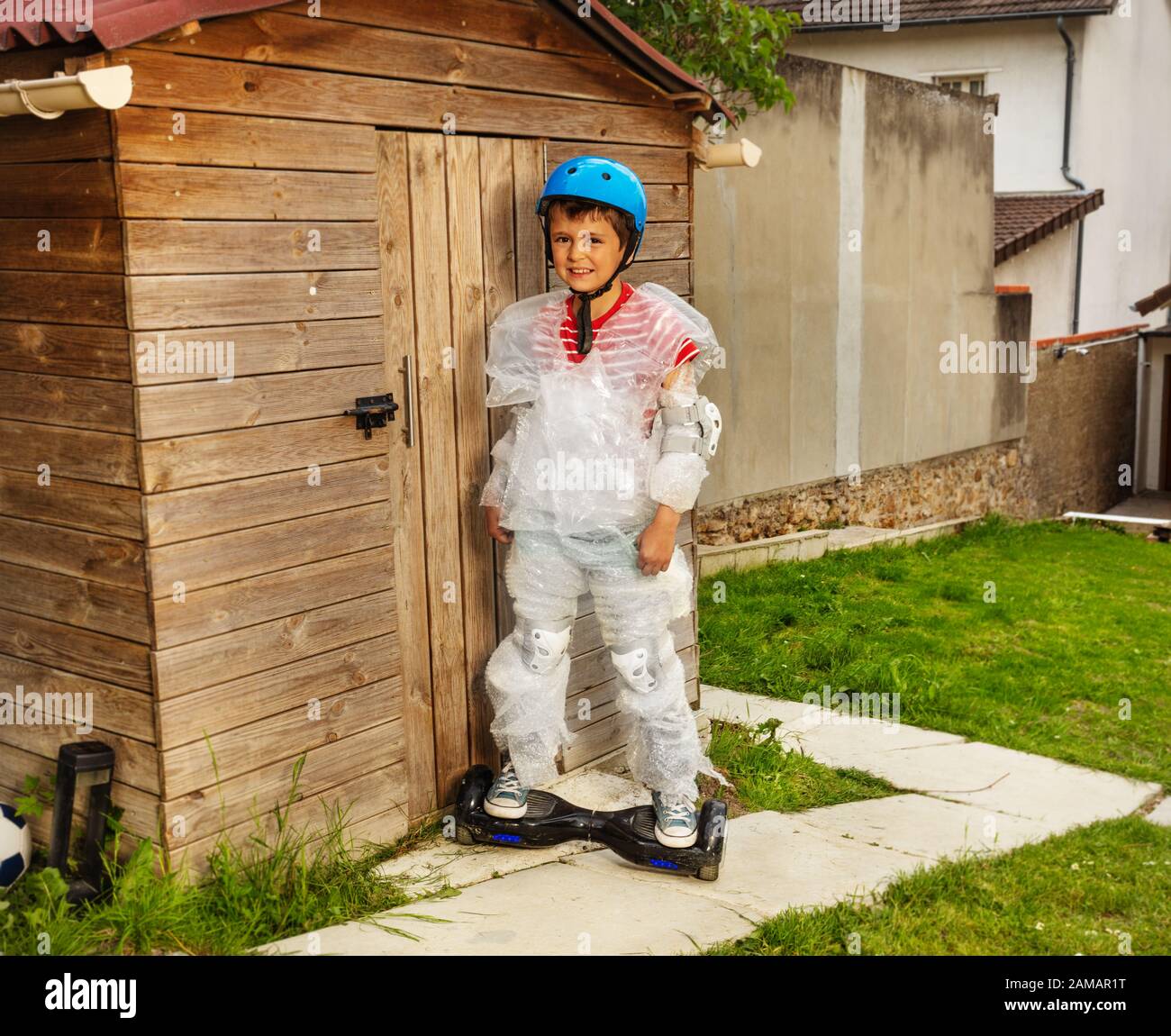 Boy ride a gyro scooter wrapped in overprotective bubble wrap and wearing helmet in the garden Stock Photo