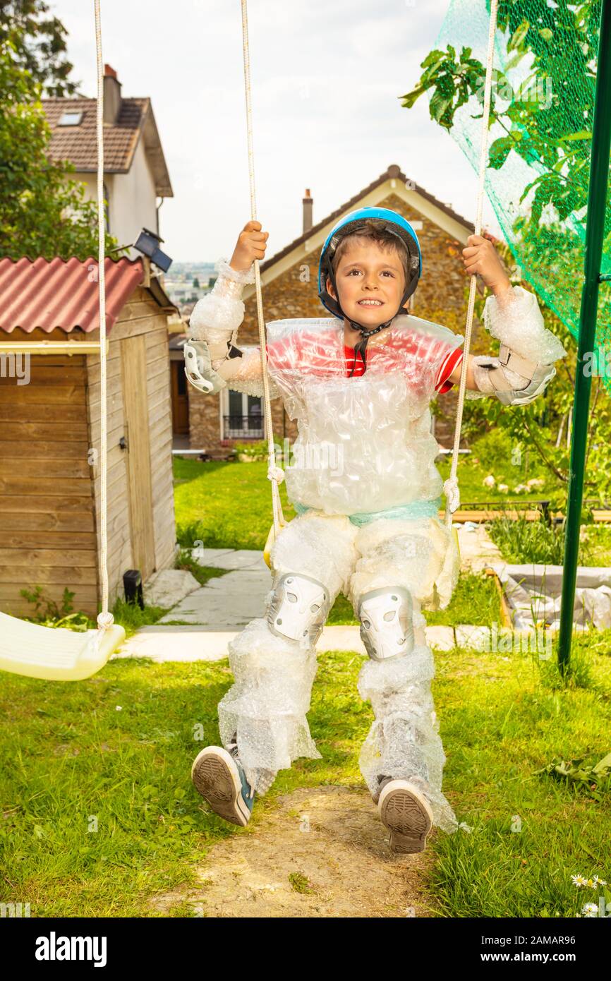 Super safe child in bubble wrap and helmet swing on swings with
