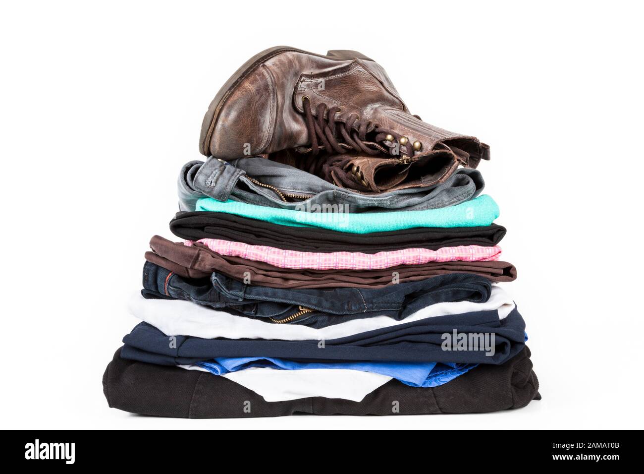 Pile of second hand clothing. A stack of old clothes folded neatly with a pair of worn boots on top Stock Photo