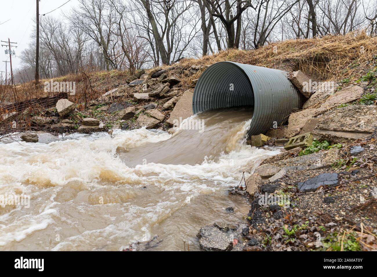 Motion blur of storm water runoff flowing through metal drainage culvert under road. January storms brought heavy rain and flash flooding to Illinois Stock Photo