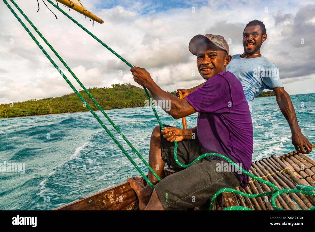 Polynesian style sailing on a Proa (multi-hull outrigger sailboat) in Deboyne Islands, Papua New Guinea. The crew consists of at least three people. One determines the angle of attack of the sail at the back. Another crew member steers by shifting weight. A loose paddle can be used to steer slightly. Stock Photo