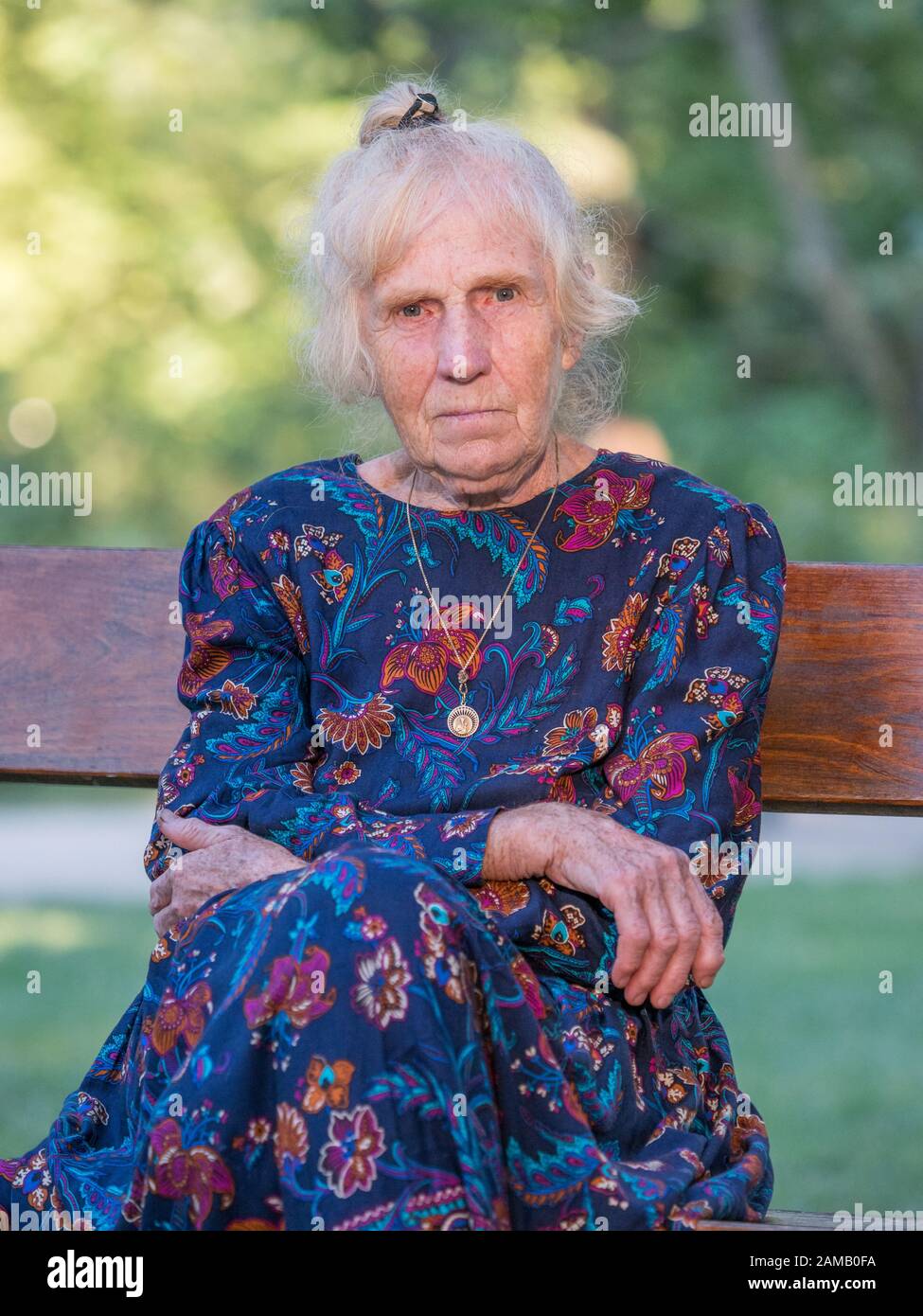 An elegantly dressed, elderly woman is sitting on a park benchis sitting on a park bench. Poland. Stock Photo