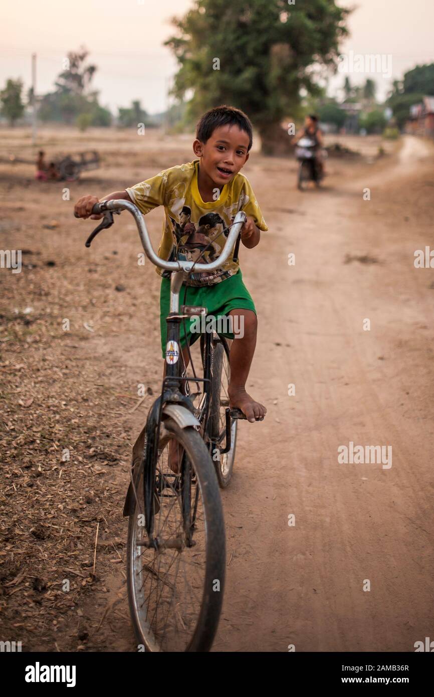 DON DET, LAOS - APRIL 5, 2013: An unidentified young boy rides a bicycle through the village of Don Det, Laos. Stock Photo