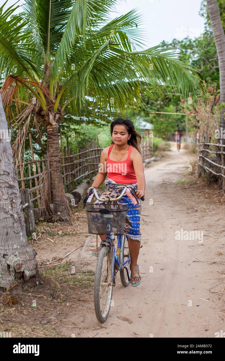 DON DET, LAOS - APRIL 5, 2013: An unidentified girl riding a bicycle through the village of Don Dhet, Laos. Stock Photo