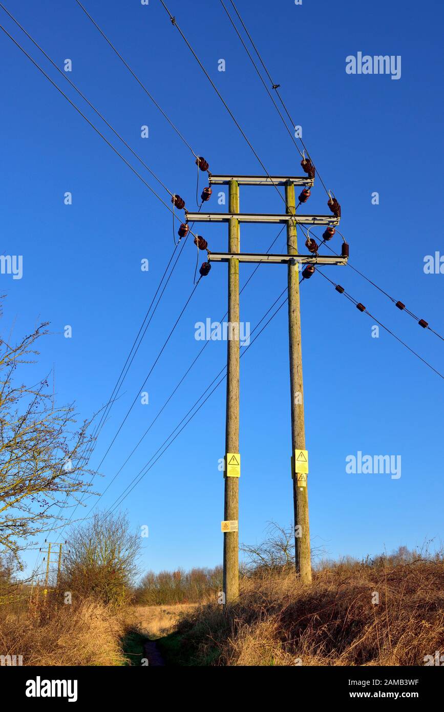 Overhead electricity power lines on wooden masts Stock Photo
