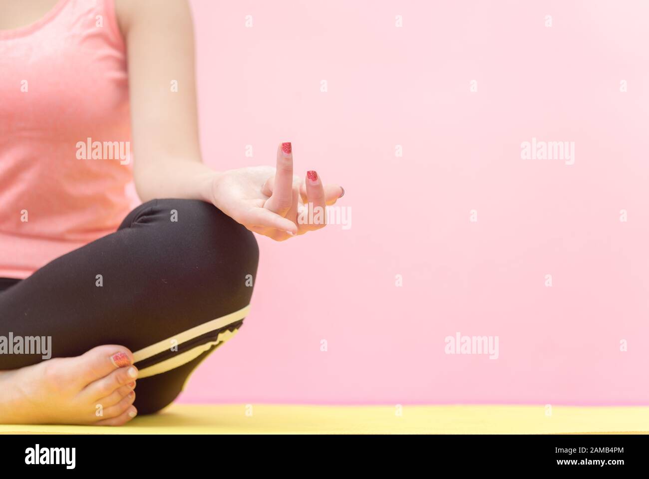 Young woman practicing yoga, sitting in Half Lotus exercise, Ardha Padmasana pose, working out, wearing sportswear, meditation session, Stock Photo