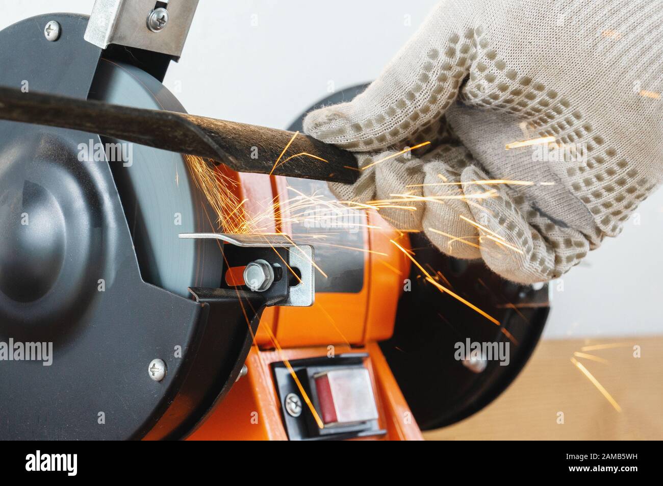 Sharpening the blade of a lawn mower with an electric sharpener. Hands
