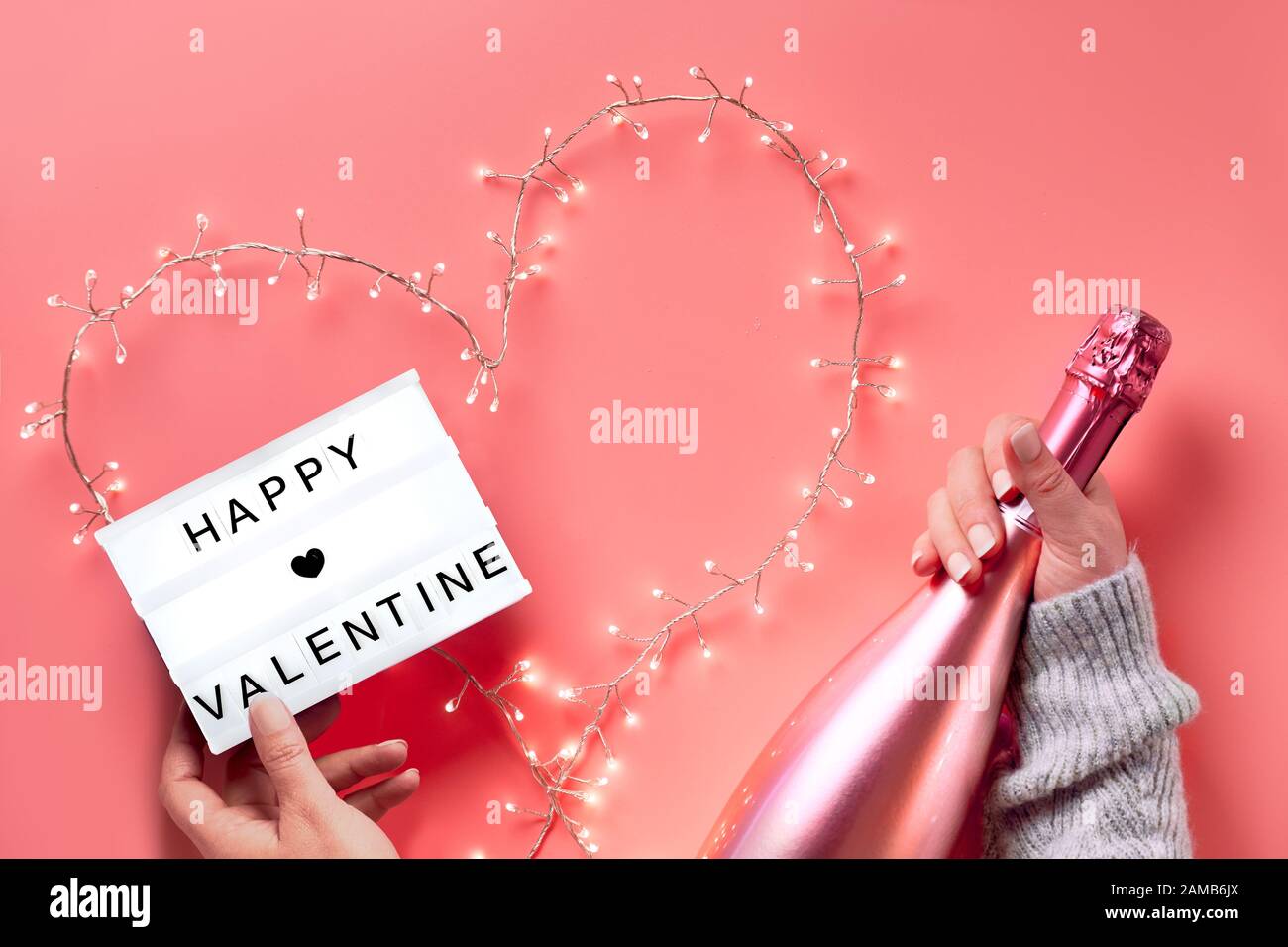 Valentine flat lay, top view on pink background. Hands holding lightbox ...
