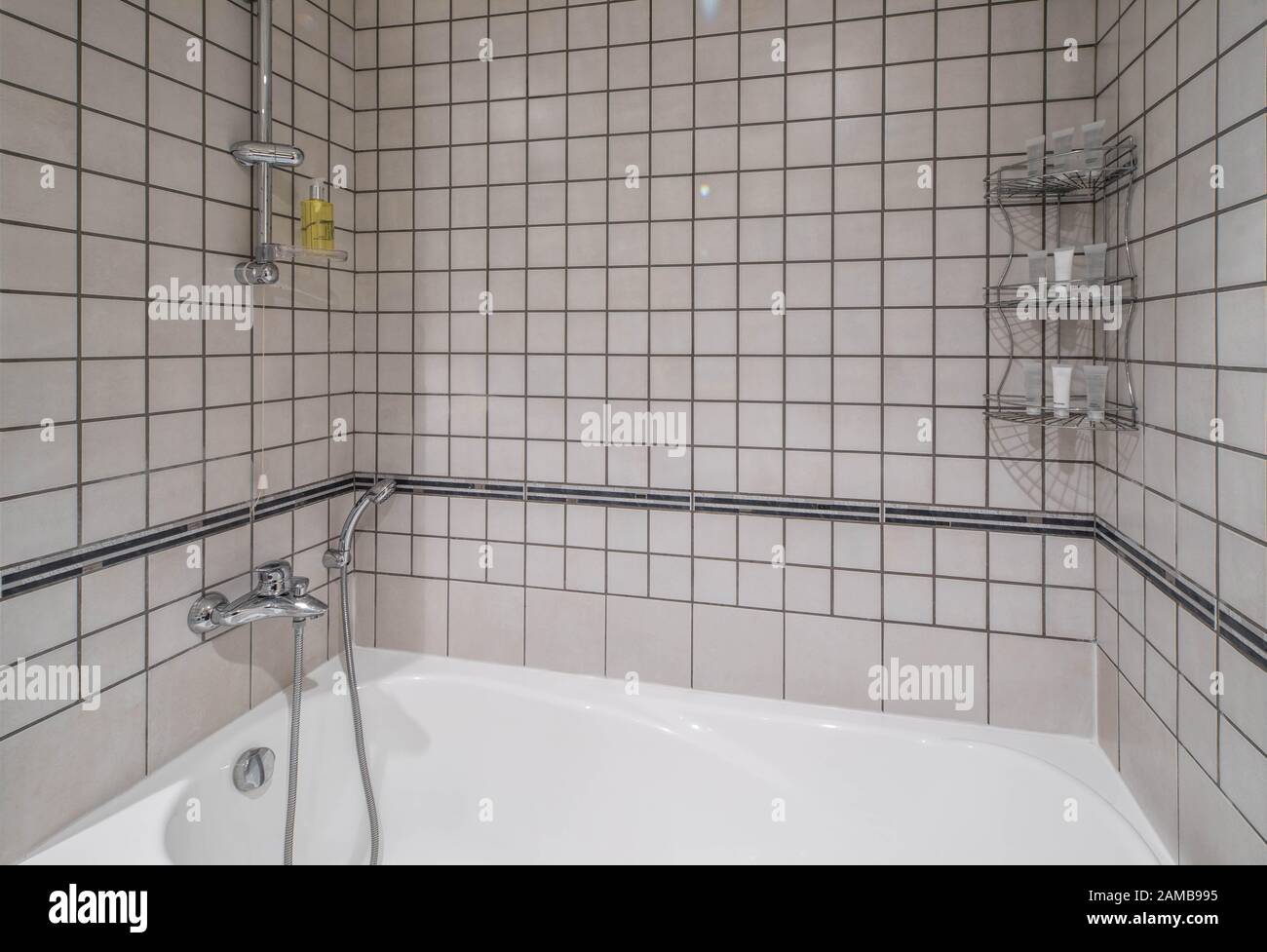 Modern interior of bathroom. Light tile. White bath with shower. Stock Photo
