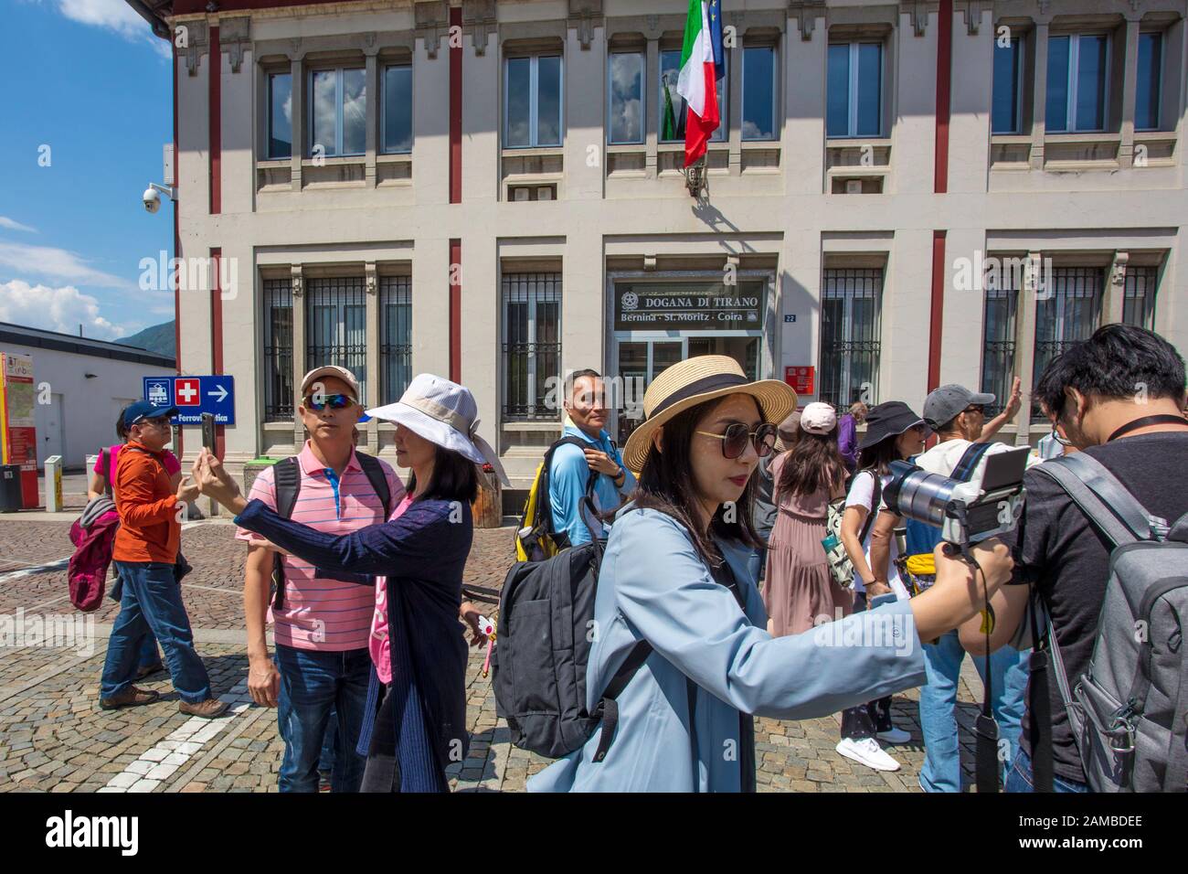 Chinese tourists take selfies while waiting for the Bernina Express which will take them to Switzerland. Tirano railway station, Italy Stock Photo