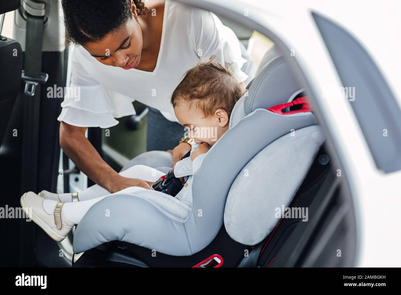 Side view of a little girl sitting in a baby seat while mother