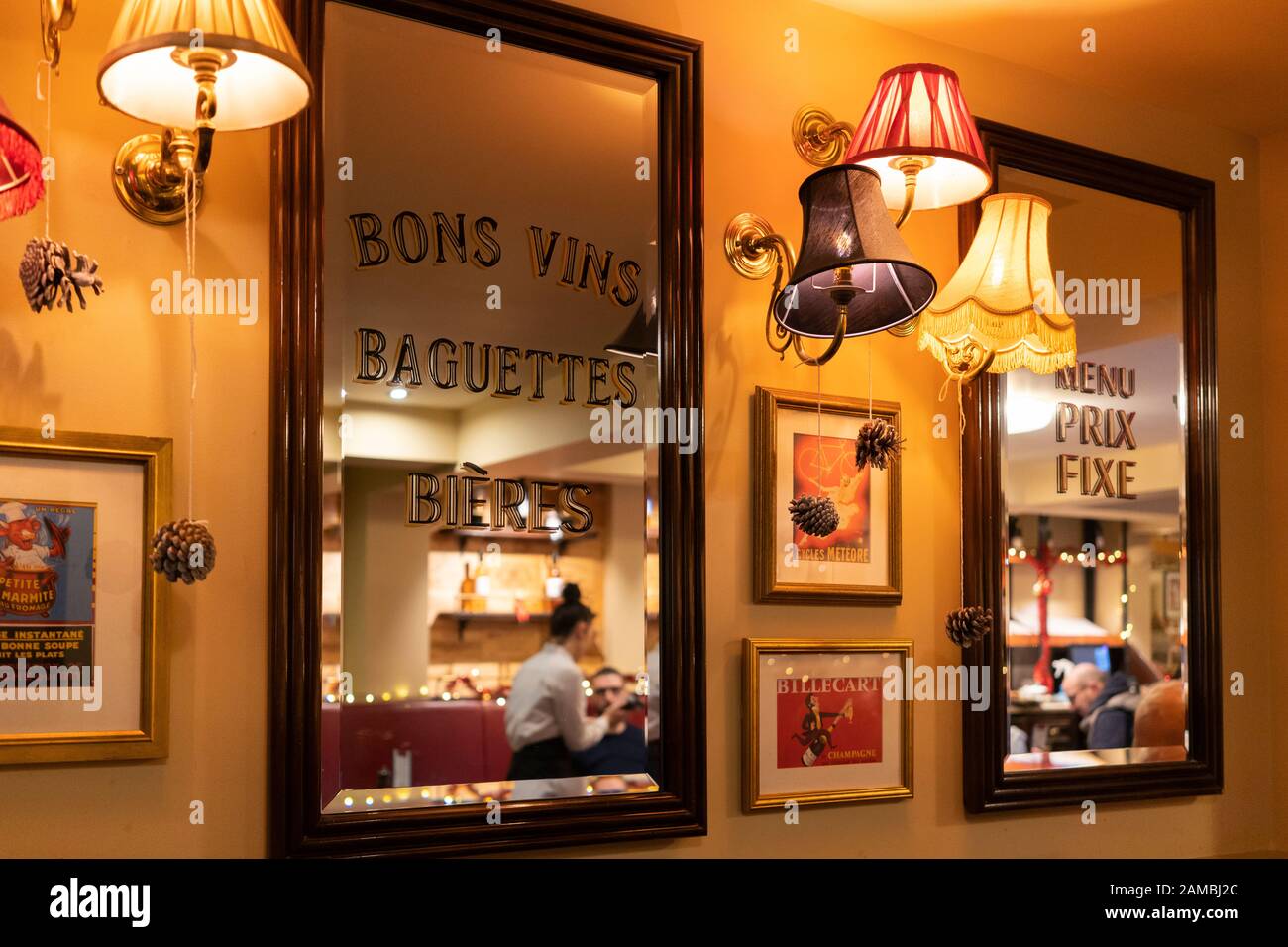 A reflection of a waitress in a mirror serving in Cafe Rouge in Stratford, with French text, UK Stock Photo