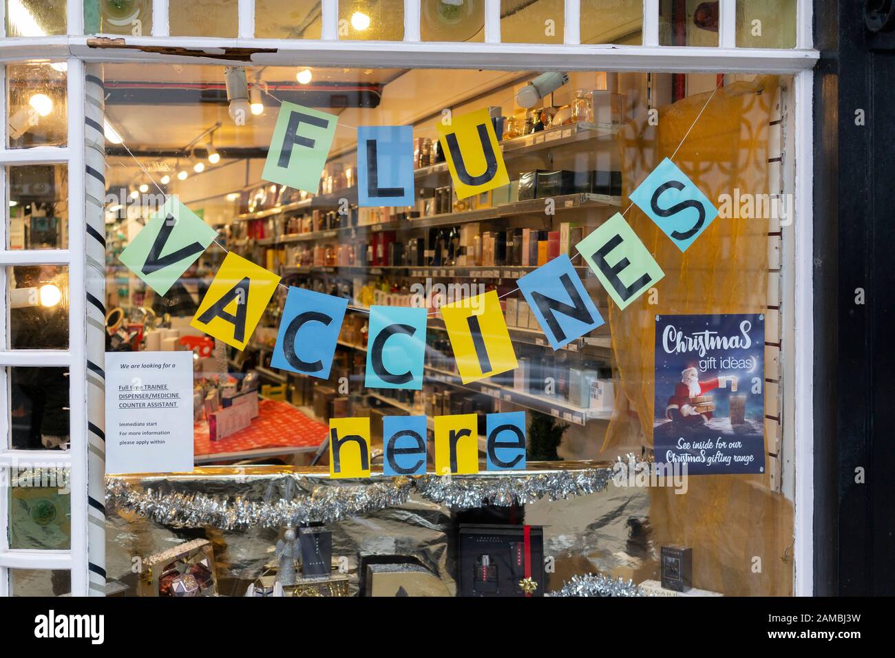 A sign saying flu vaccines here in the window of Stratford Pharmacy, Stratford-upon-Avon at winter time, UK Stock Photo