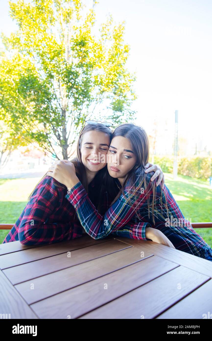 View at two sad best female friends embracing each other Stock Photo