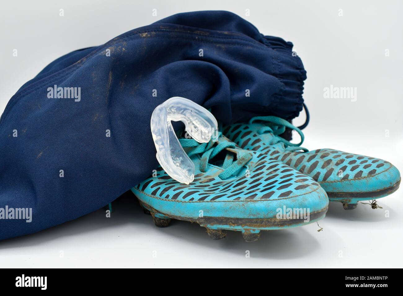 dirty rugby gear on a white background. Rugby boots, shorts and gumshield mouthguard Stock Photo