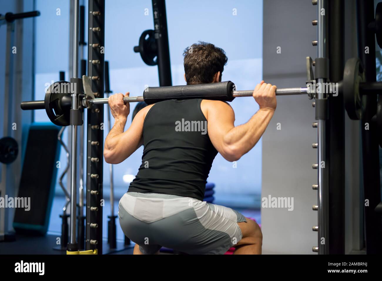 Bodybuilder doing squats using a squat cage in a gym to train his legs Stock Photo Alamy