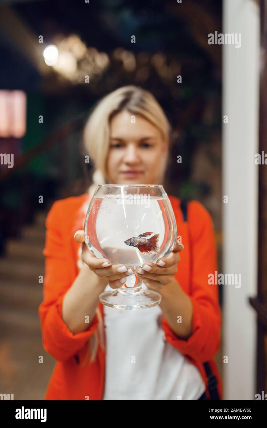 Young woman holds glass with fish, pet store Stock Photo