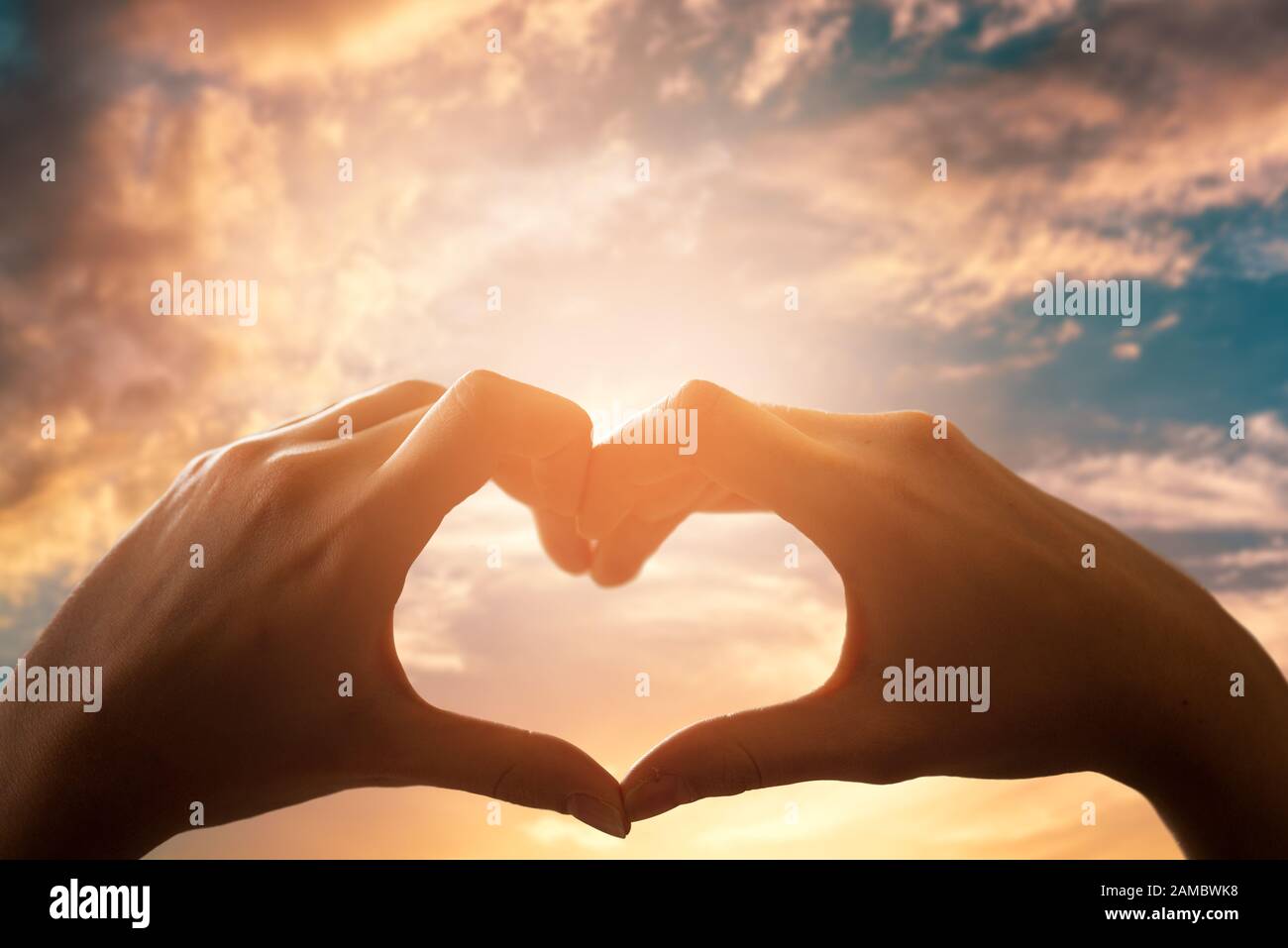 Two hands are getting heart shape formation with the sun light passing through the hands Stock Photo