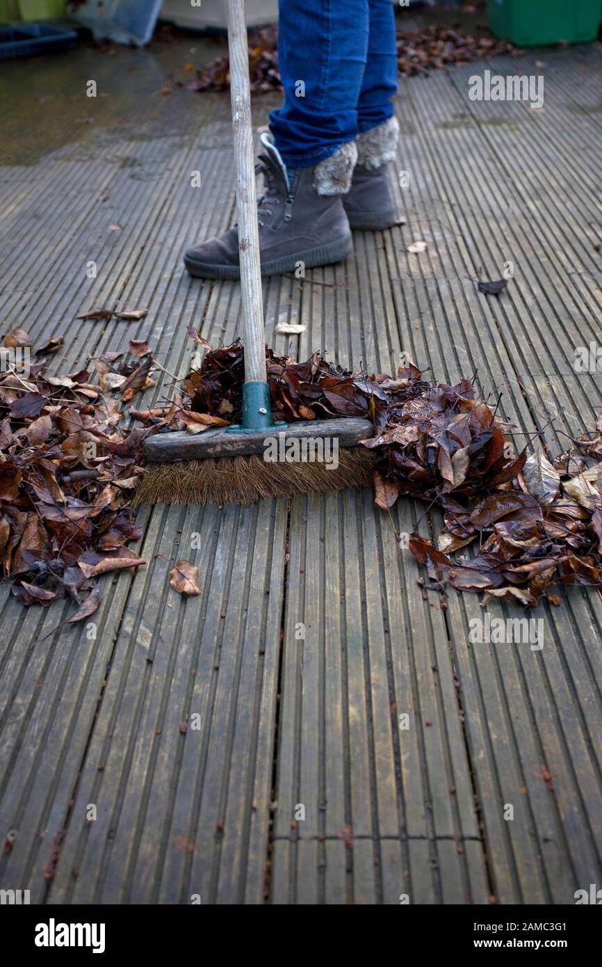 Sweeping down the decking of old leaves Stock Photo
