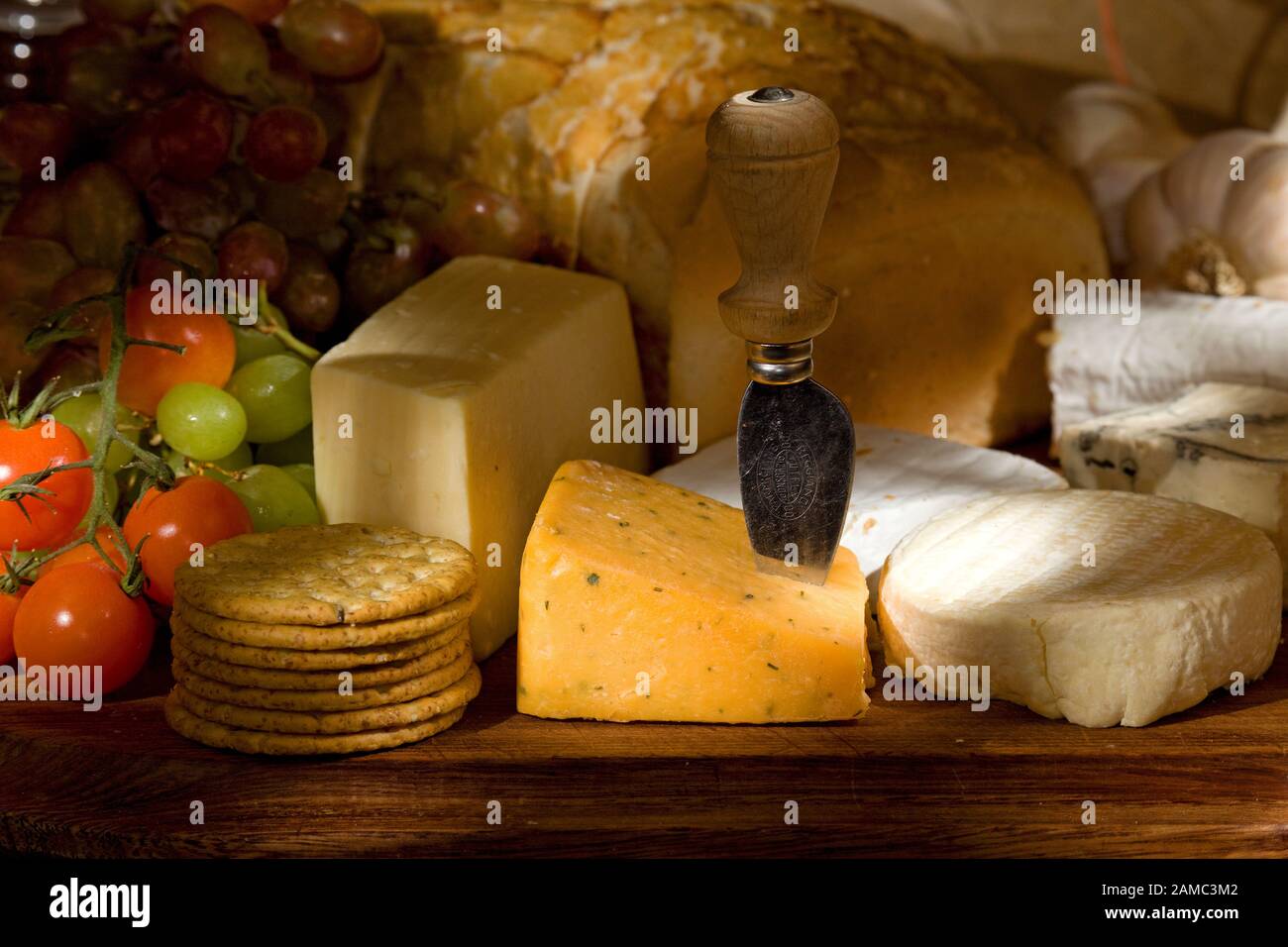 Cheese board with assorted cheeses fruits and vegetables Stock Photo