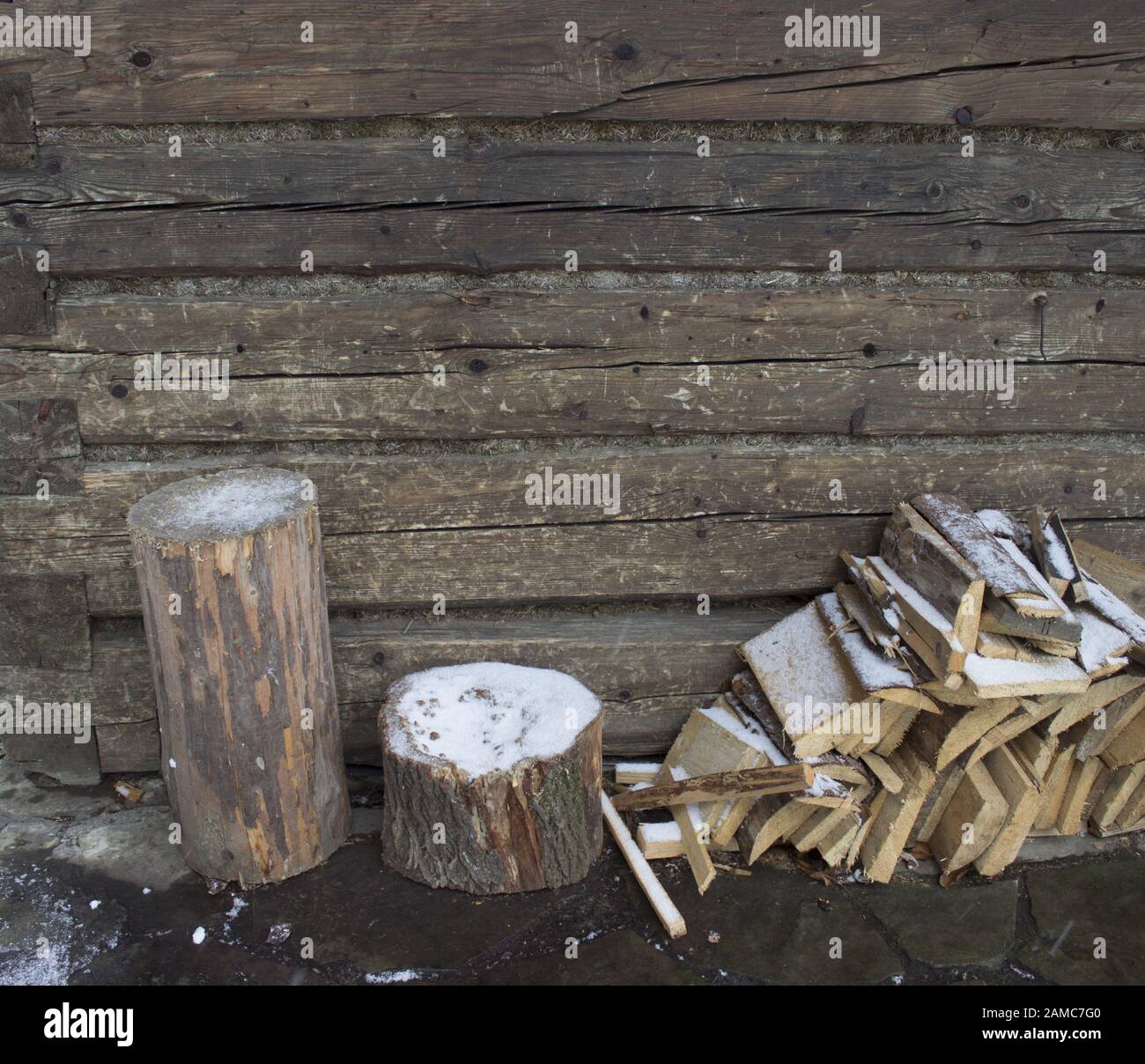 Firewood and logs for chopping firewood near log cabin wall Stock Photo
