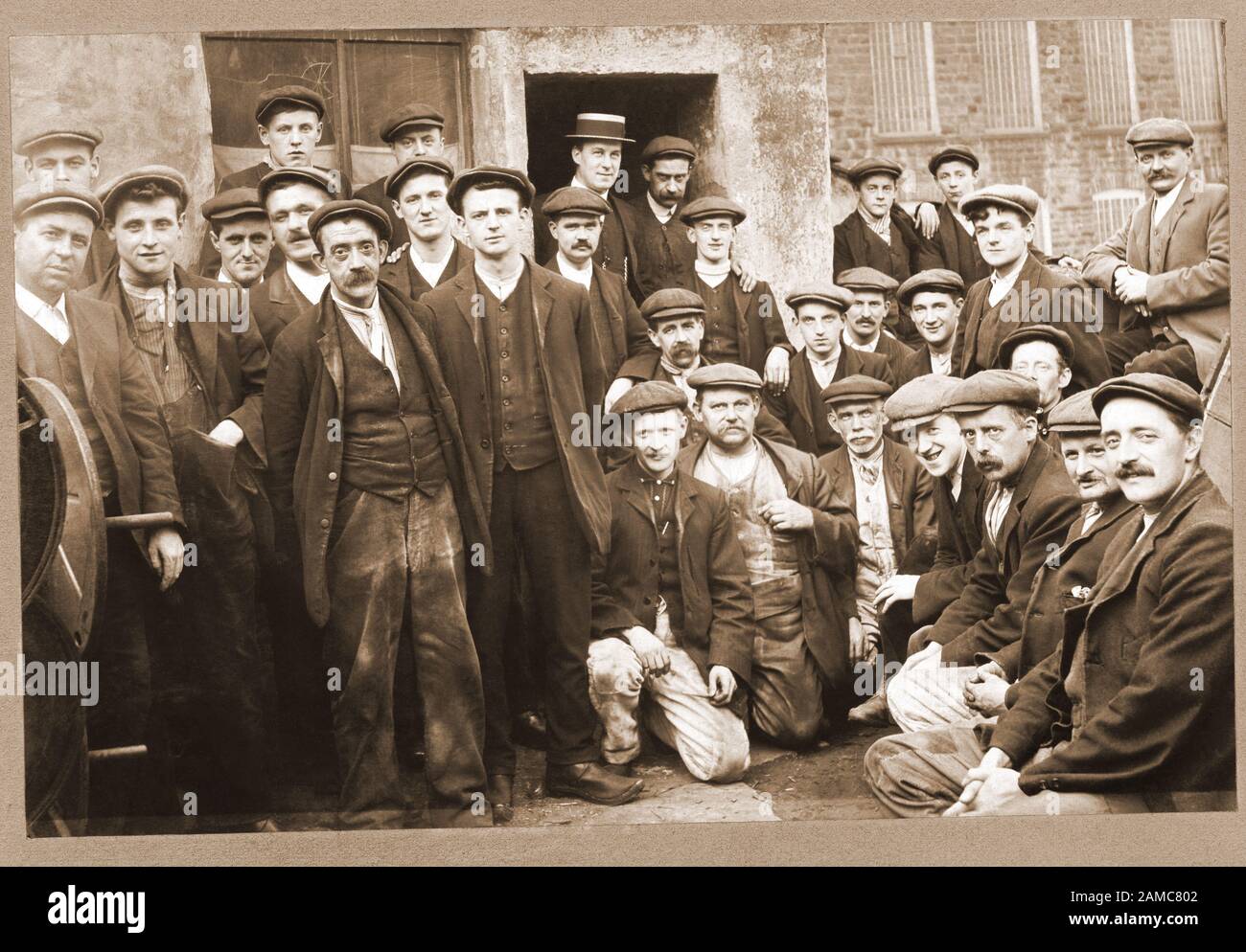 Workers, social structure. Gaffer, boss, cloth cap, Boss. Victorian group of workers in traditional working clothes outside a factory. Stock Photo