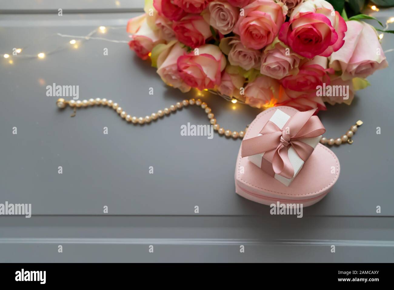 Rose pink flowers bouquet with jewellery on gray table with gift box ...