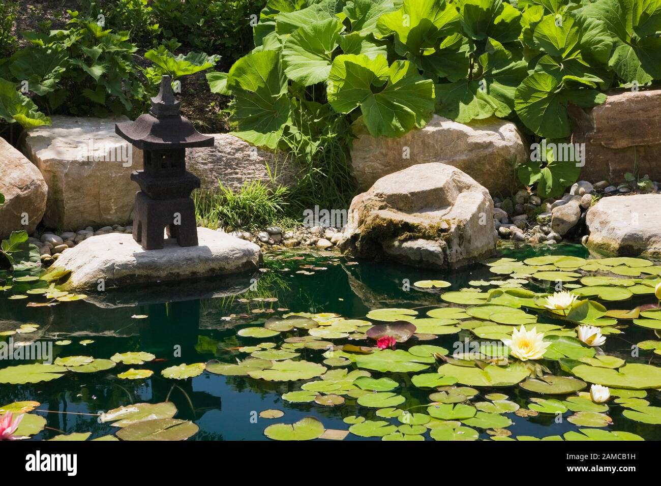 Pond with ornamental sculpture in the Zen garden at the 'Route des Gerbes d'Angelica' garden in spring, Mirabel, Quebec, Laurentians, Canada. Stock Photo