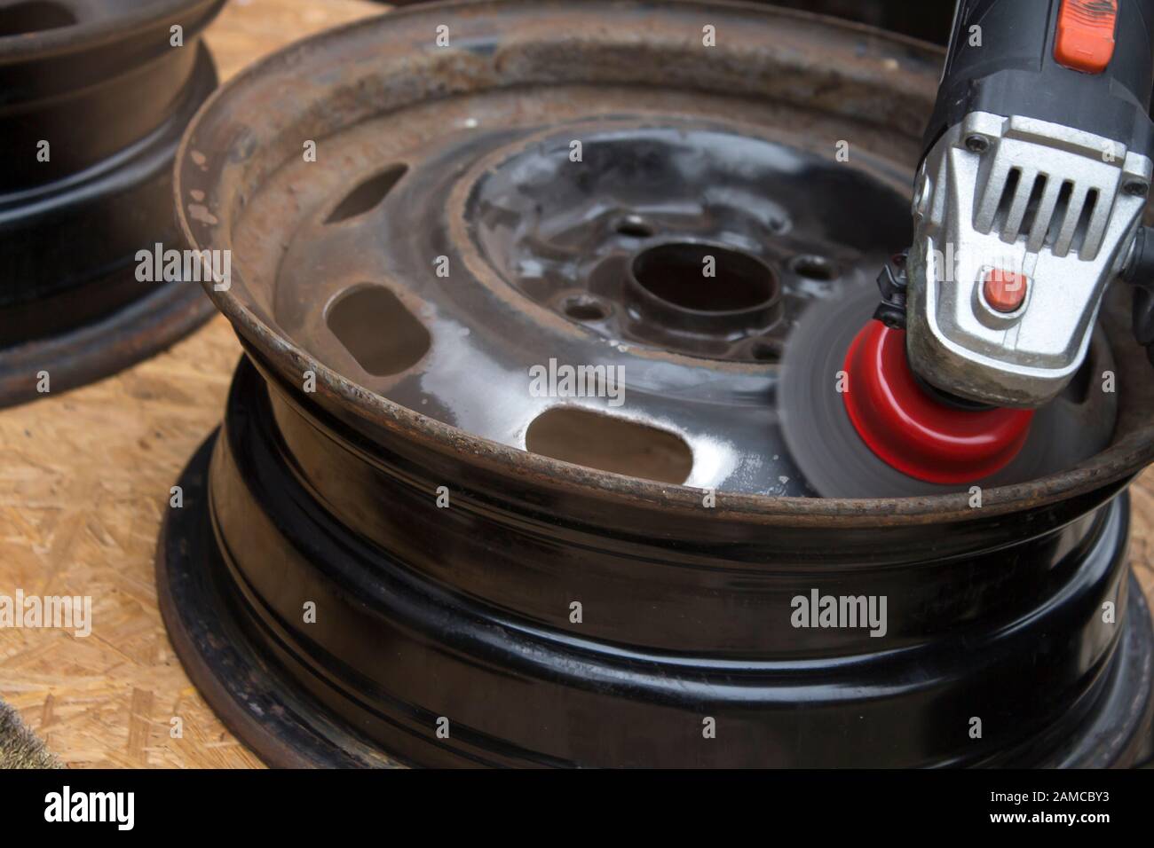 Clean the steel wheel rim with a wire brush attached to the grinder. Stock Photo