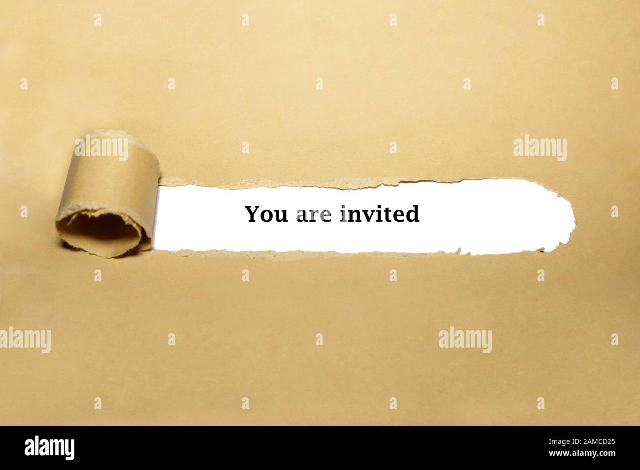 Text You Are Invited appearing behind torn brown paper - Invitation concept. Stock Photo
