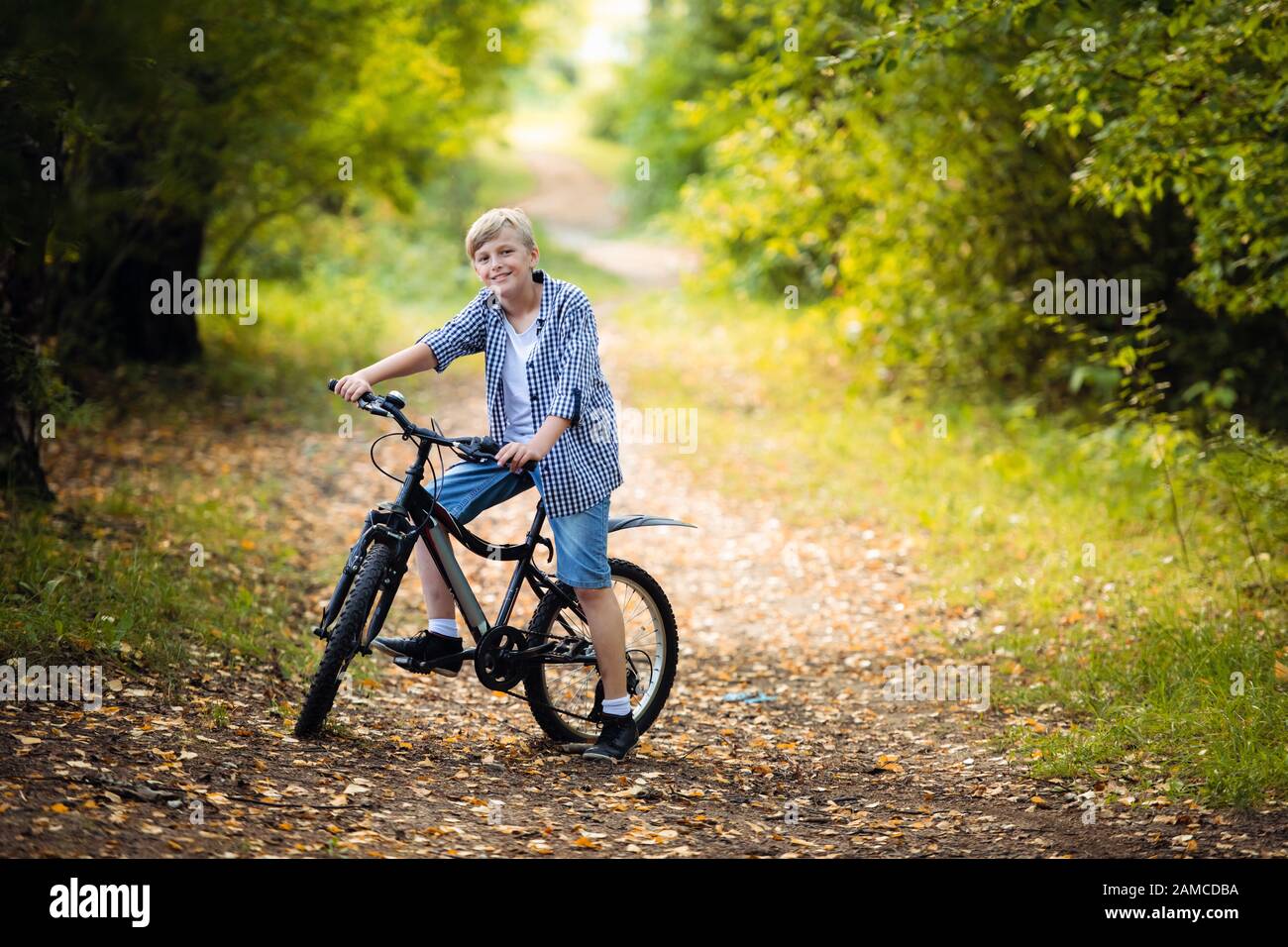 Teen Boy Rides A Bicycle Along A Path In The Forest The Cyclist Rides Fast Through The Springboards Stock Photo Alamy