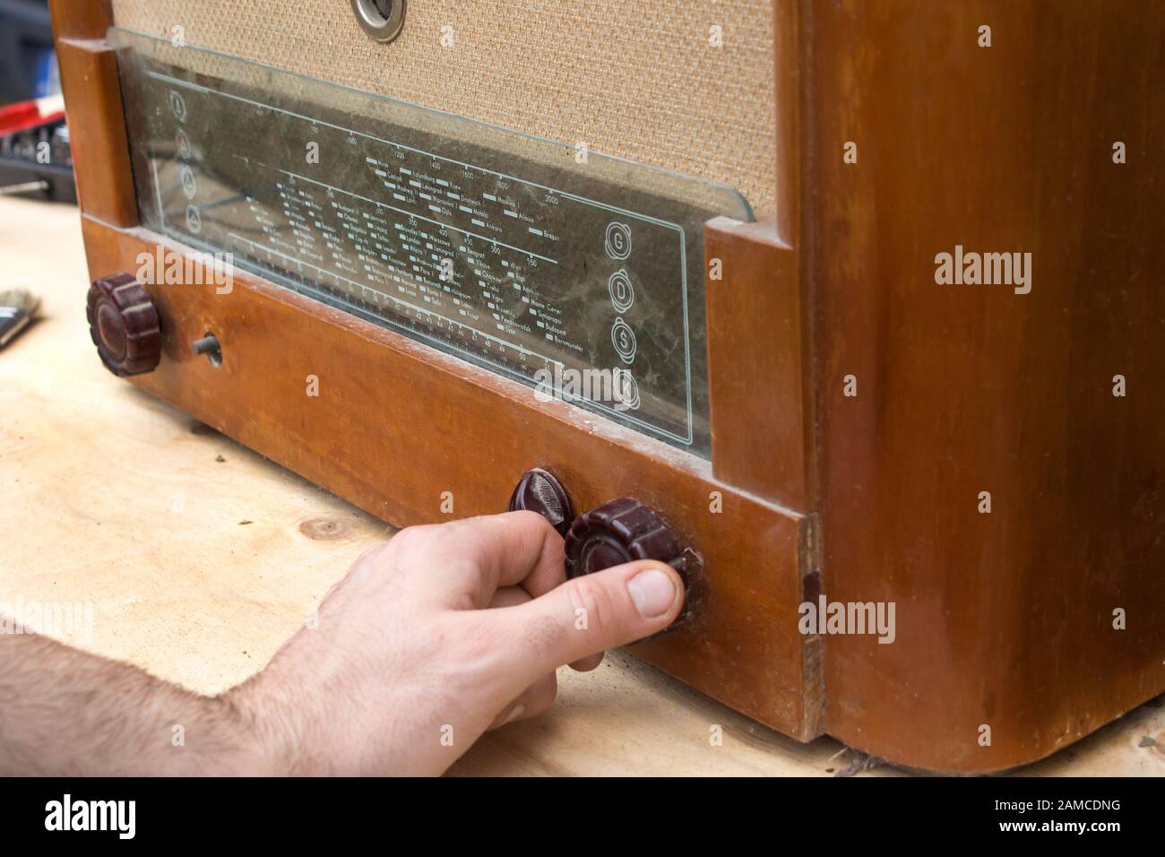 The man's hand adjusts the potentiometer scale in the old vintage radio tube. Stock Photo