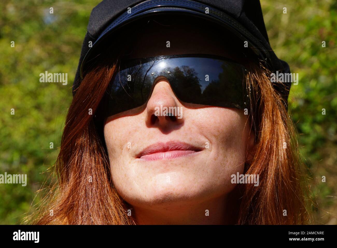 Portrait  junge rothaarige Frau mit modischer Sonnenbrille und schwarzer Kappe Stock Photo