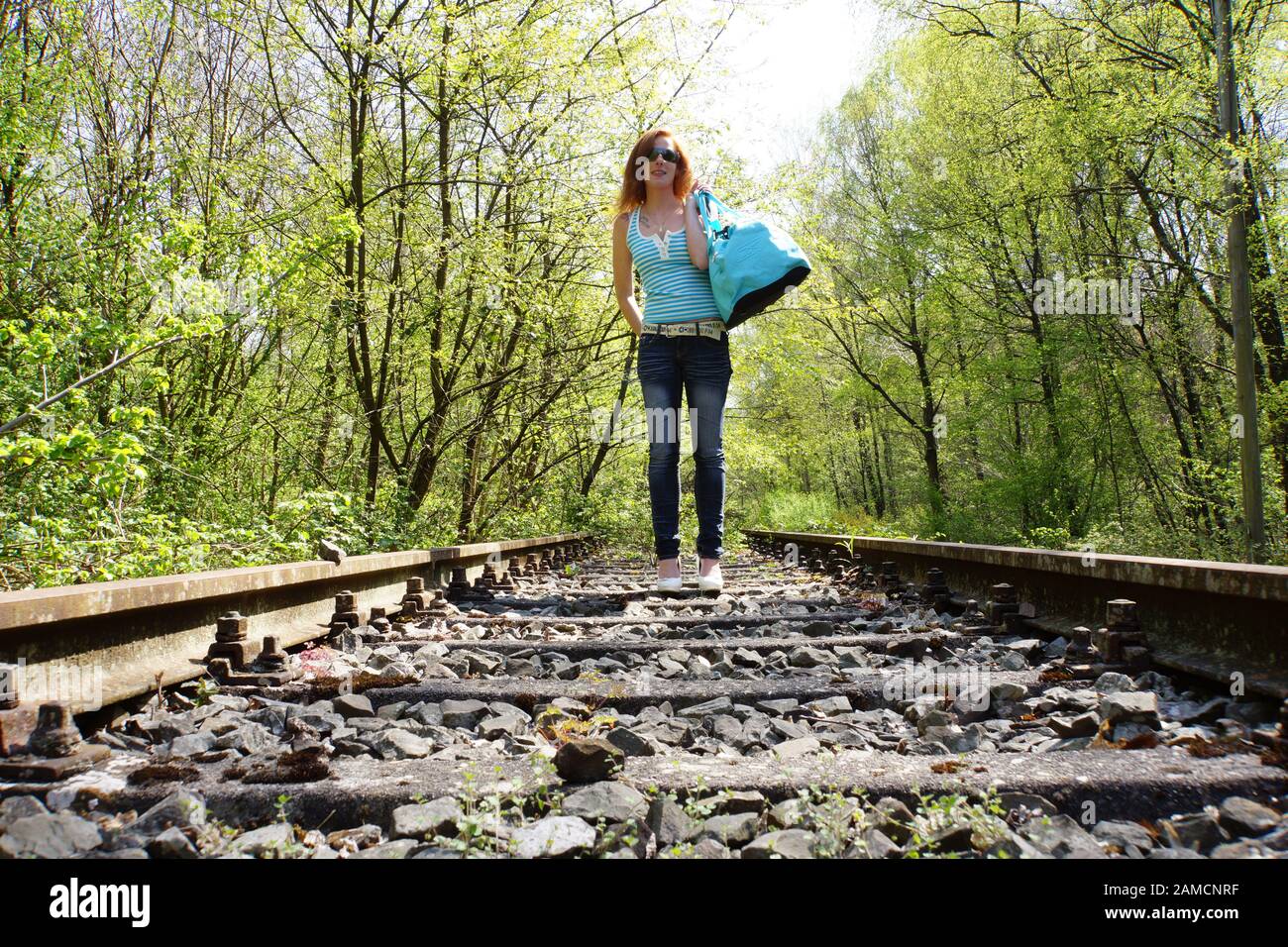 junge Frau mit Reisetasche an altem Bahngleis Stock Photo