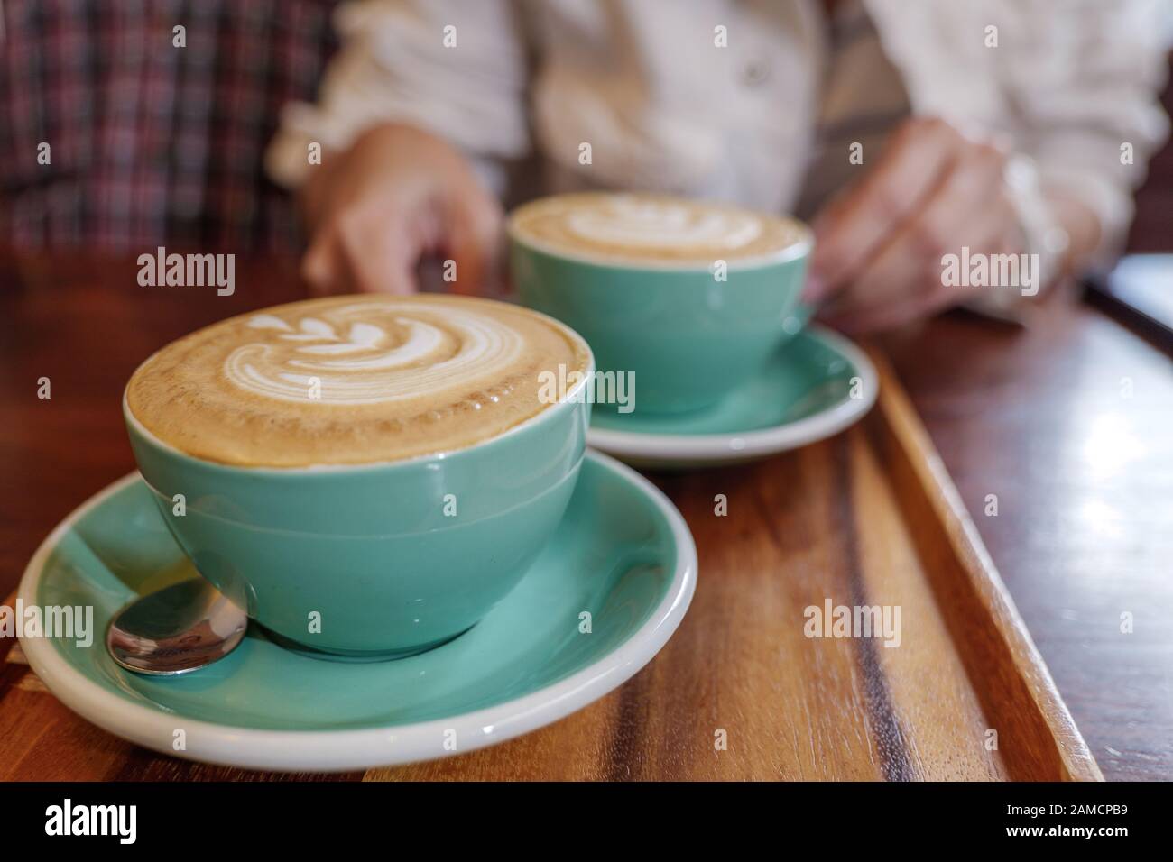 Two cups of cappuccino with small heart and leave pattern of latte art