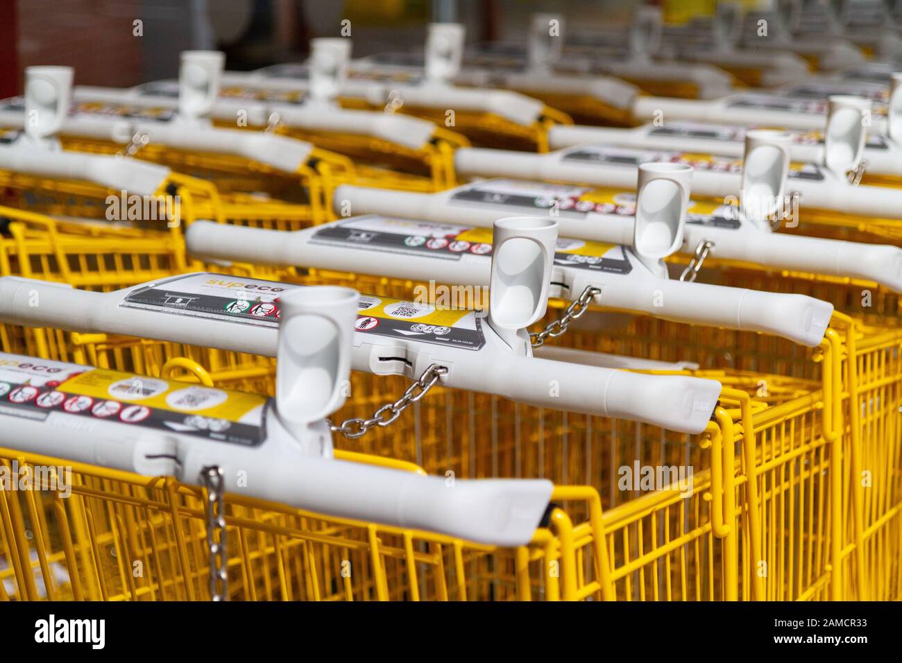 Rows of yellow branded shopping trolleys (carts) at a supermarket in France. Stock Photo