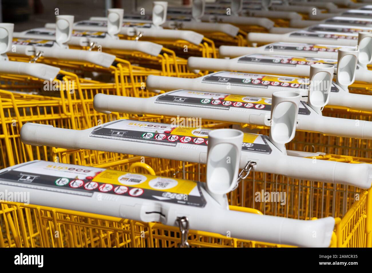 Rows of yellow branded shopping trolleys (carts) at a supermarket in France. Stock Photo