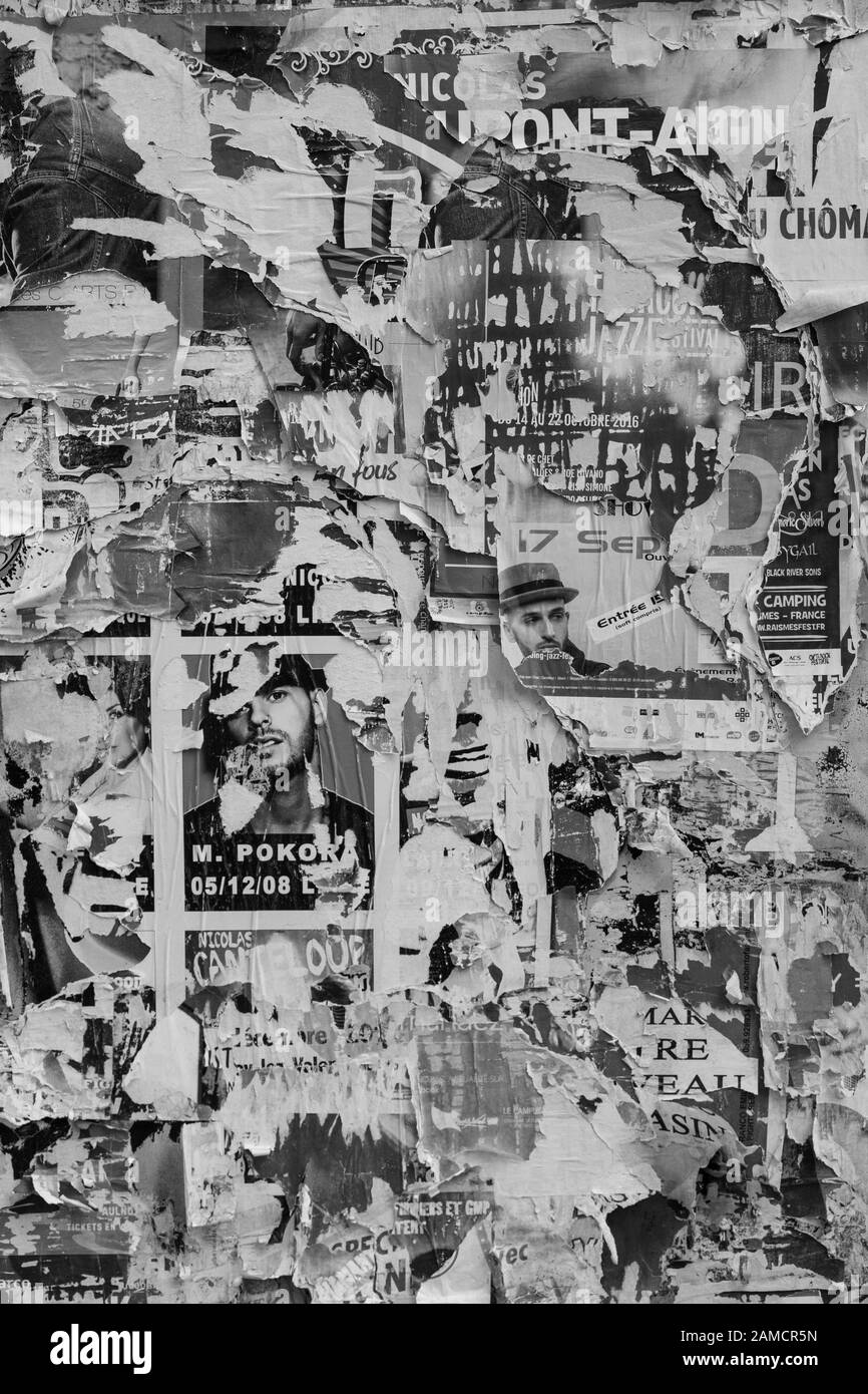 A street wall plastered with countless advertisements, most of them torn, shredded and weathered. Stock Photo