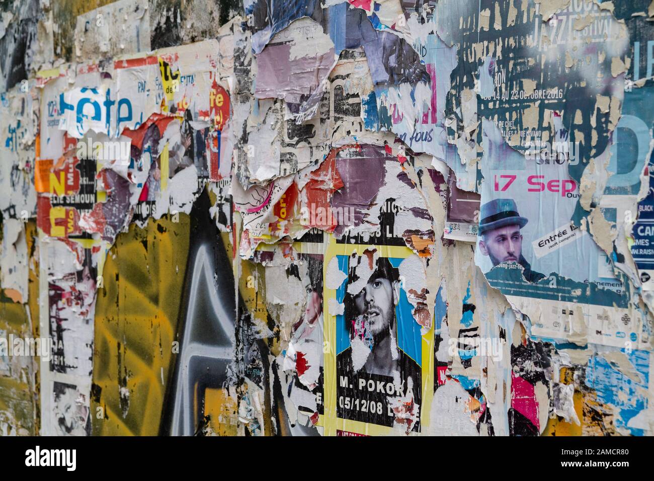A wall on the street with countless advertisements, most of them torn and shredded. Stock Photo