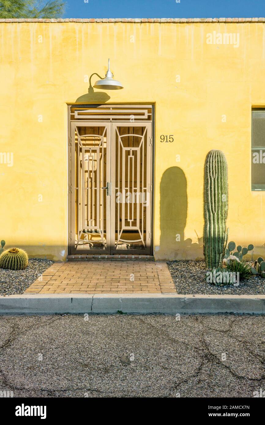 entrance doors & intricate metal gates set into facade of yellow stucco renovated house are signs of gentrification in Barrio Historic District Tucson Stock Photo