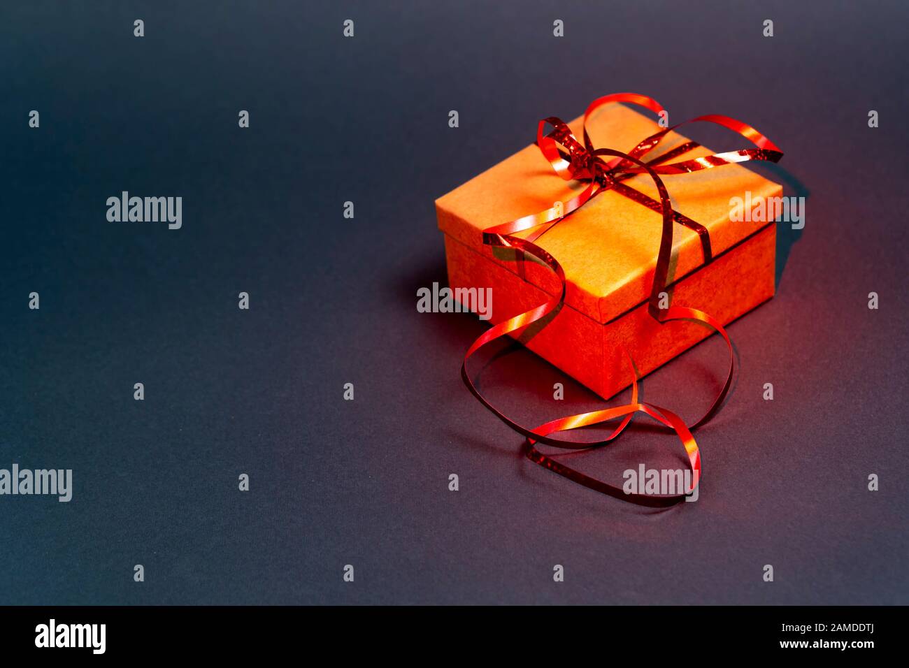 Gift box with red ribbon on a gray background. Red backlight Stock Photo
