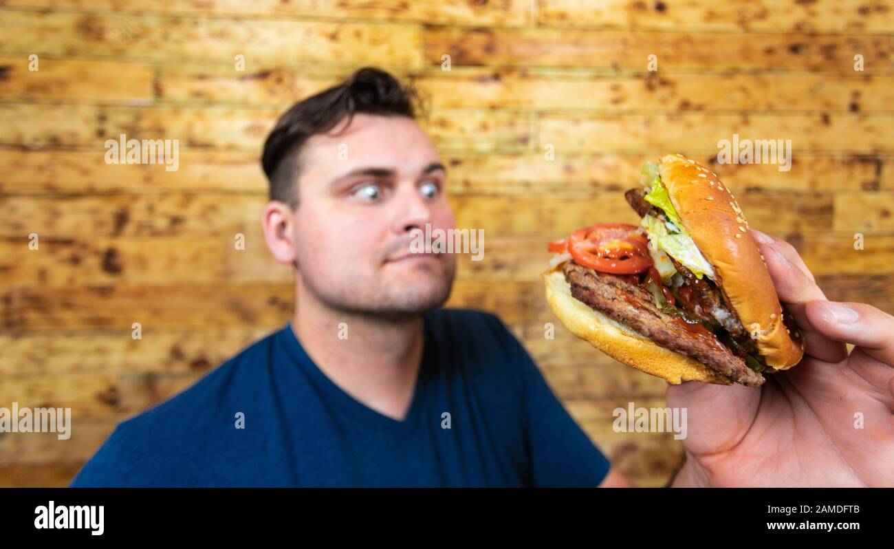 Happy man with his fast food burger. Not so much healthy life style, but whatever! Stock Photo